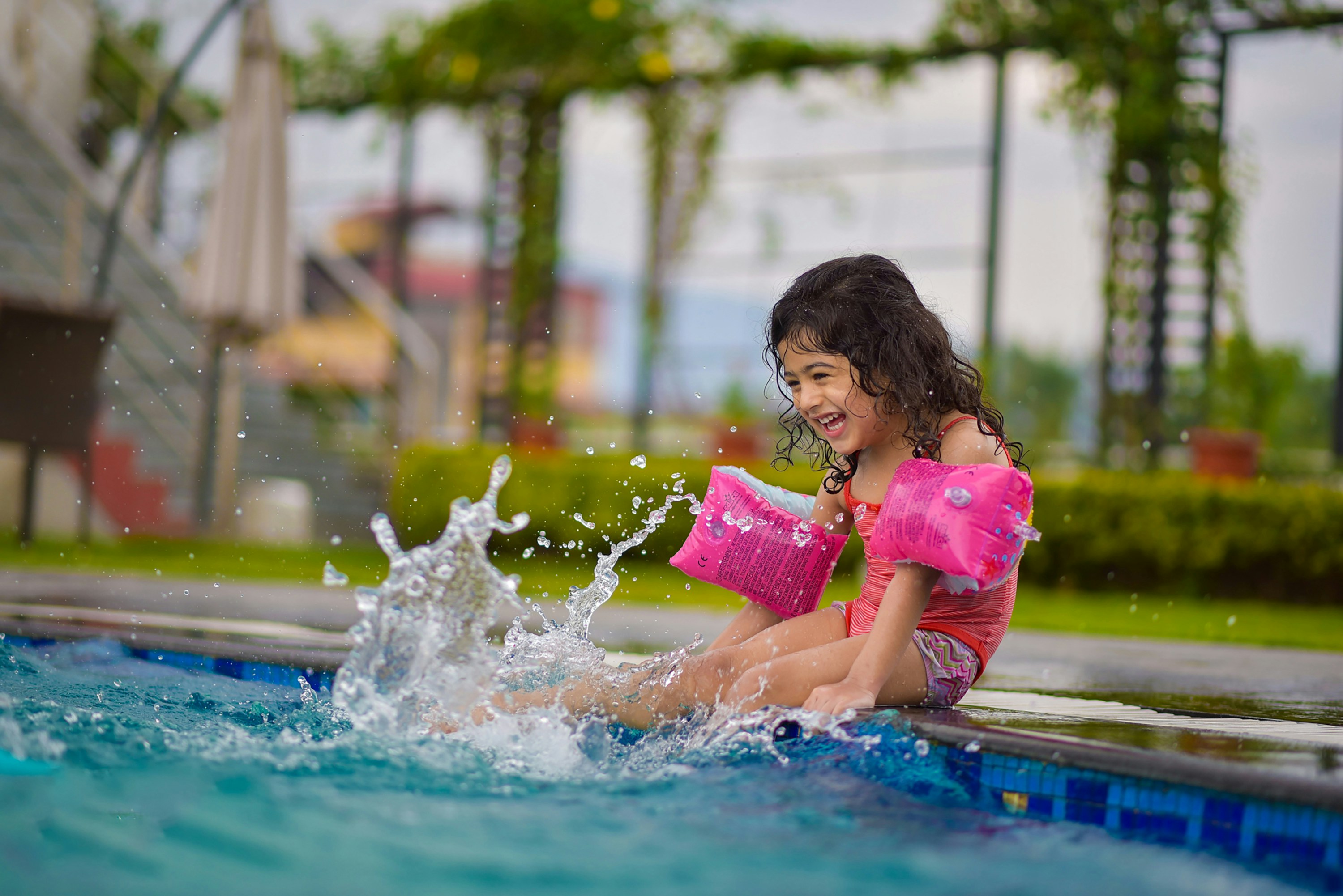 petite fille assise au bord d'une piscine